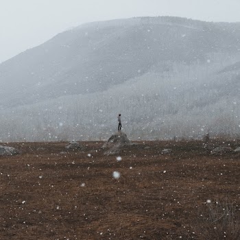 The man standing on the boulder in winter