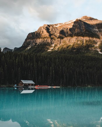 The morning sun bathes the peaks of glaciers, while the lake remains hidden in the shadows
