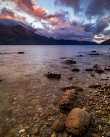 The setting sun creates a colorful sky above Lake Wakatipu, New Zealand. 