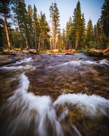 The sun begins to set behind a set of cascades in Yosemite National Park, CA, USA.