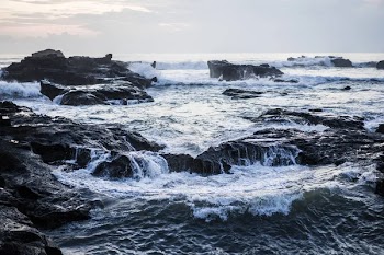 The waves of the ocean are breaking against the rocks. splashing ocean waves at sunset.