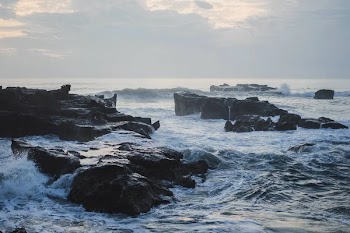 The waves of the ocean are breaking against the rocks. splashing ocean waves at sunset.
