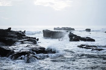 The waves of the ocean are breaking against the rocks. splashing ocean waves at sunset.