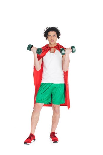 Thin sportsman with dumbbells in hands and wearing red cape isolated on white