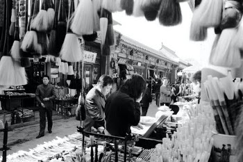 This was totally intentional; to frame the scene with paint brushes on sale in the market.
