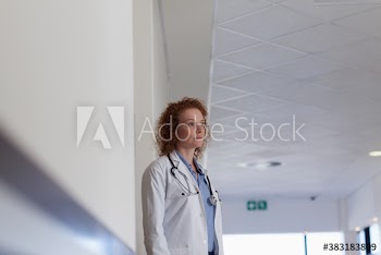 Thoughtful female doctor looking away in hospital corridor
