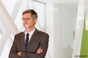 Thoughtful mature corporate businessman with arms crossed