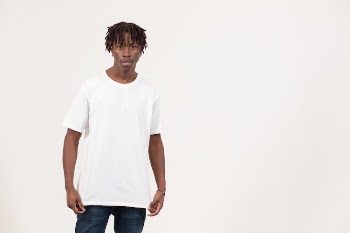 Thoughtful young black guy in t shirt standing in white studio