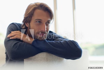 Thoughtful young man leaning on sofa