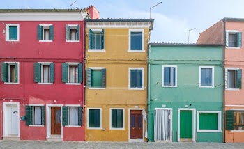 three assorted-color concrete houses under blue and white sky at daytime