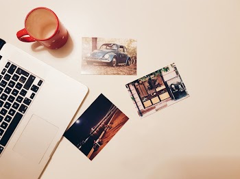 Three Assorted Photos on Desk Beside Laptop and Mug
