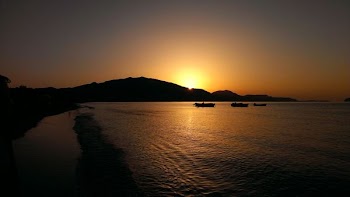 three boat sailing on ocean near shore during sunset
