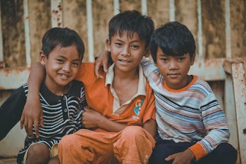 Three Boys Sitted Next to Each Other Holding Around the Shoulders