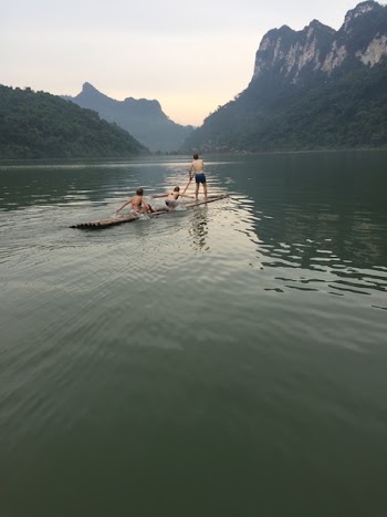 Three Children on Brown Boat in Body of Water