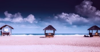 Three Gray Nipa Huts on Shoreline
