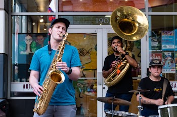 Three Man Playing Drums And Wind Instruments In Front Of Store