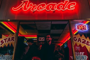 three men inside arcade game station