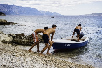 Three Men Pushing Speed Boat on Seashore