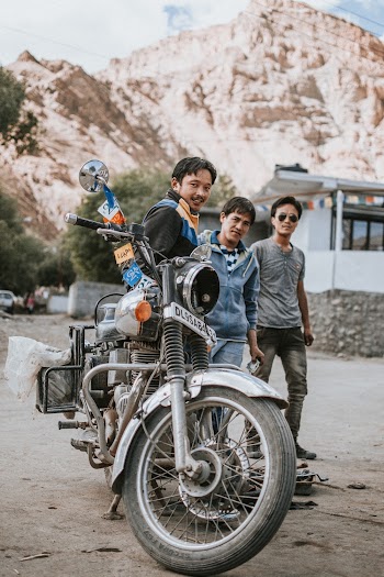 Three Men Standing Near Black Motorcycle Beside House