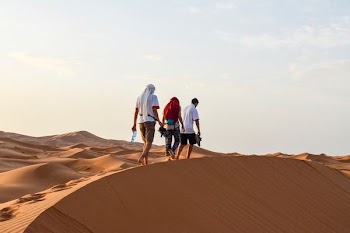 three men walking on desert during daytime