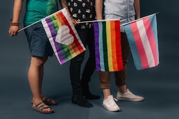 Three People Holding Pride Flags Feet