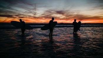 three people holding surf boards in ocean