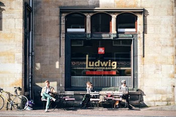 Three People Sitting on Bench in Front of Ludwig Coffee Bar