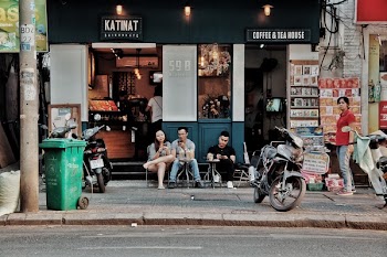 Three People Sitting on Chairs Outside Coffee &amp; Tea House Near Motorcycles