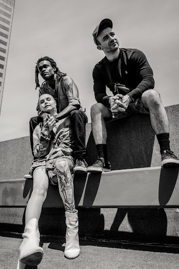 Three People Sitting on Concrete Fence