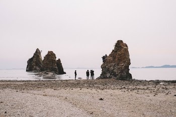 three people standing near brown rock formation