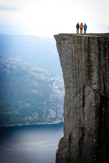 three people standing on cliff