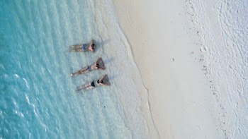 three people sunbathing on shoreline