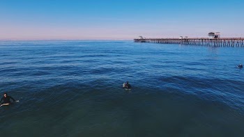 three people swimming on ocean under blue sky