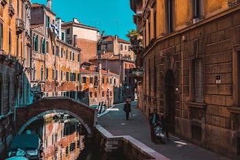 three people walking on alleyway beside canal during daytime
