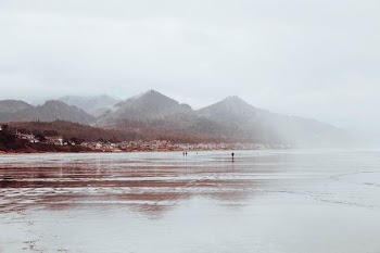 three person standing on water with mountain background