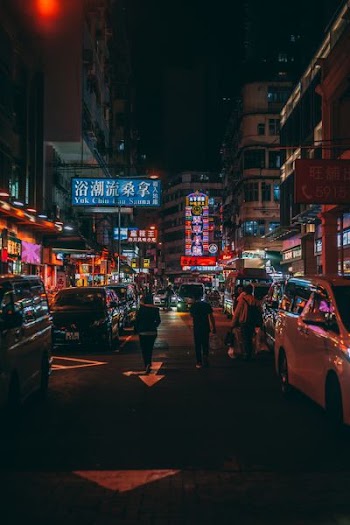 three person walk beside cars