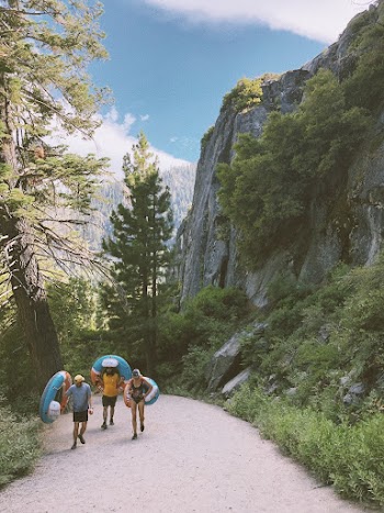 Three Person Walking in a Road Near Cliff