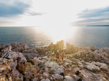 Three Persons Standing on Rock