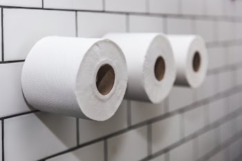 Three Rolls Of Toilet Paper On White Tile Wall