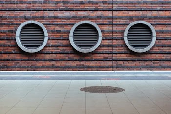 three round black tunnel on brown concrete brick building at daytime