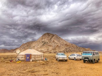 Three Vehicles Beside Mountain Under Cloudy Sky