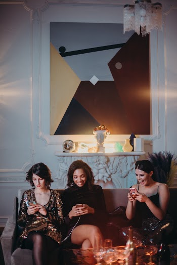 Three Women Sitting on Brown Sofa