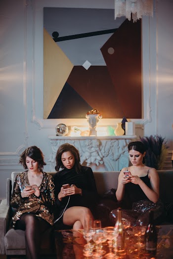 Three Women Sitting on Sofa Using Smartphone