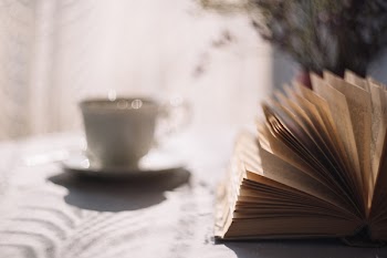 Tilt Lens Photography of Open Book With Ceramic Cup in Saucer