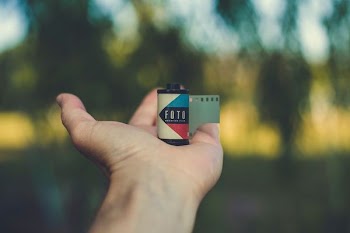 tilt shift focus photography of person holding multicolored film cartridge during datime