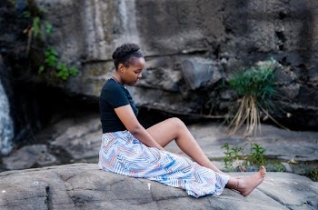 Tilt-shift Lens Photography of Woman Sitting on Top of Gray Rock