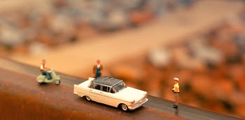 Tilt-shift Photography of Classic Car Scale Model Near Two Figurines