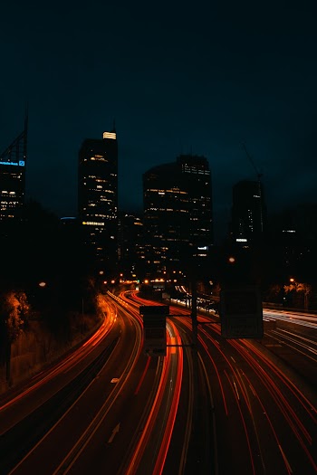 Time Lapse Photo of Lighted Highway at Night With Buildings in Background