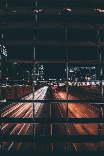 time-lapse photo of road with light streaks view behind grills