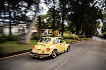 time lapse photo of running yellow Volkswagen Beetle coupe on road